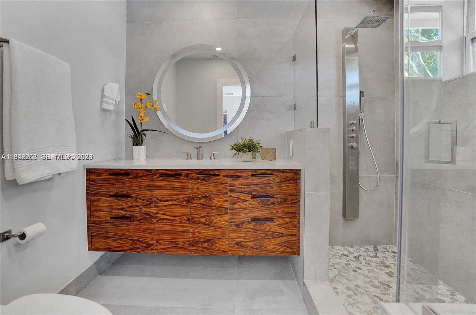 2011 Northeast 31st Court Lighthouse Point, FL 33064 - Photo 22 of 33 a bathroom with a mirror a shower and a sink