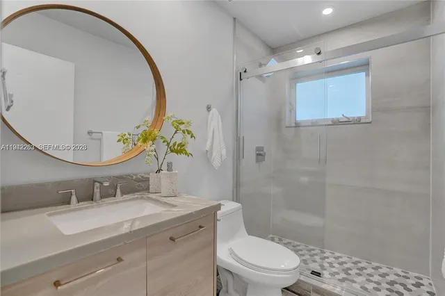 a bathroom with a granite countertop sink mirror vanity and toilet