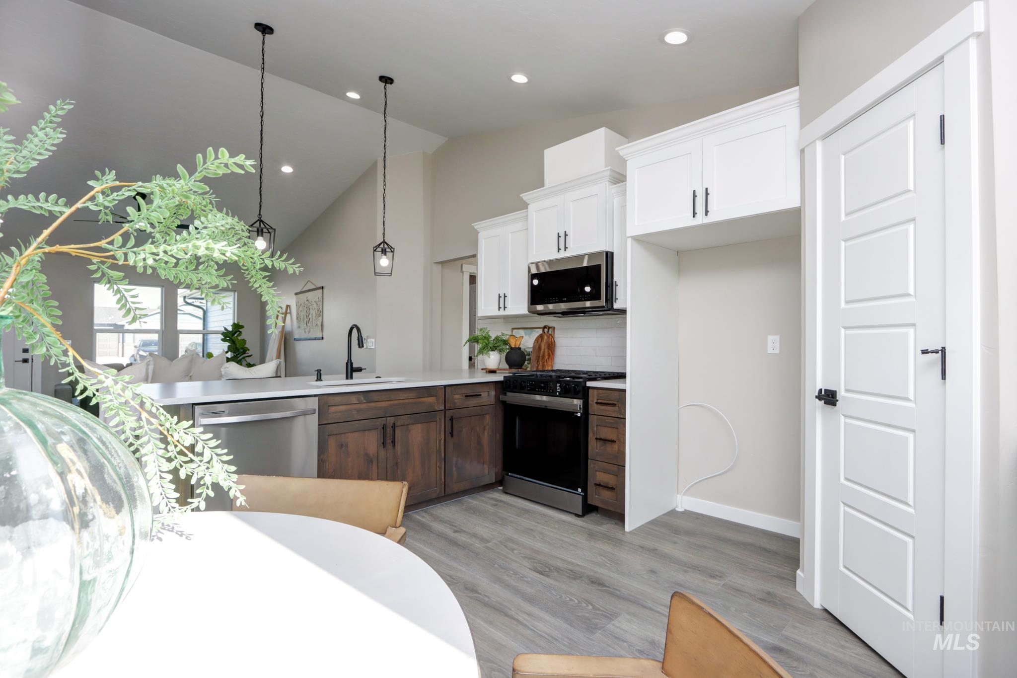 848 North 5th Street Nyssa, OR 97913 - Photo 12 of 49 Modern kitchen featuring two-tone cabinetry, stainless steel appliances, a white subway tile backsplash, and a large island with a gooseneck faucet