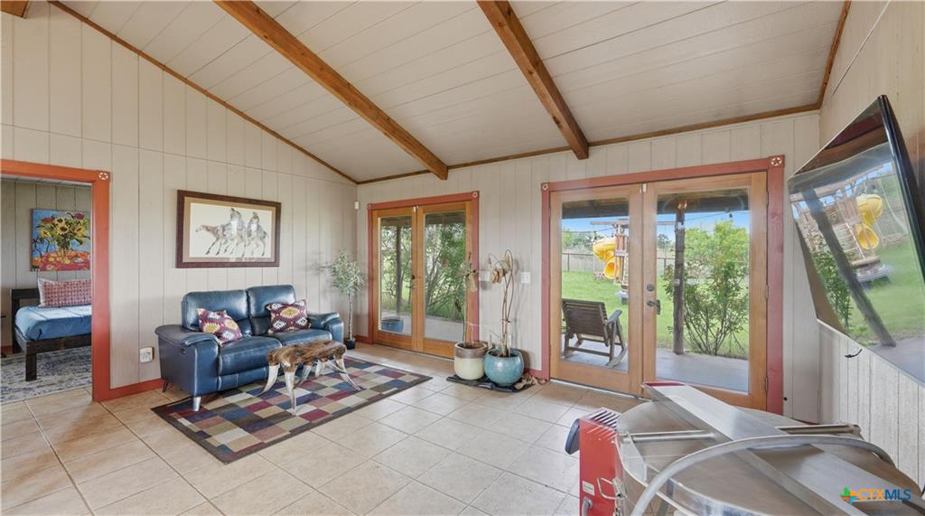 127 Offer Llano, TX 78643 - Photo 16 of 40 Vaulted ceiling with exposed wood beams, tile flooring, and double glass-paneled doors to the exterior