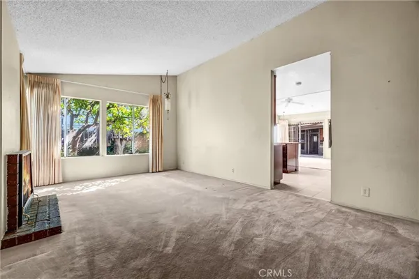 a view of an empty room with a fireplace and a window