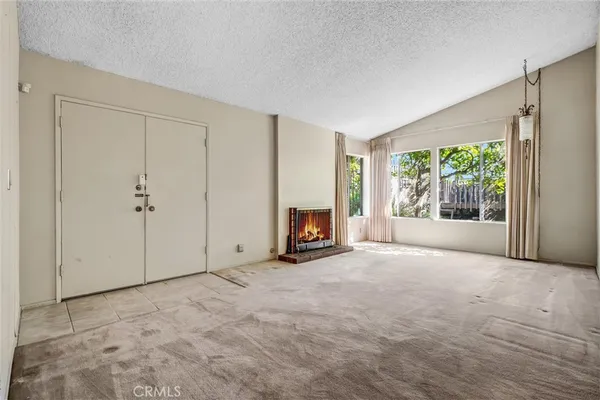 a view of an empty room with a fireplace and a window