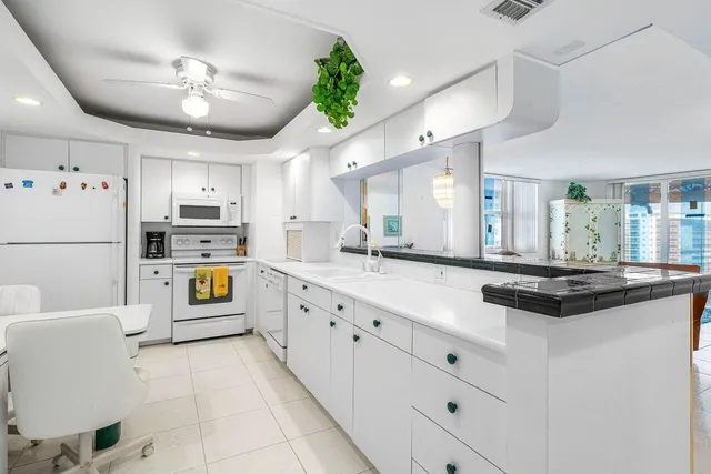 a kitchen with stainless steel appliances a refrigerator a sink dishwasher a dining table and chairs with wooden floor