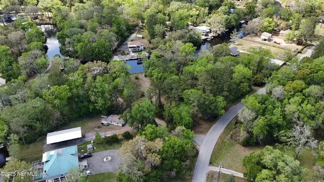 an aerial view of residential house with outdoor space and trees all around