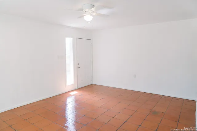 an empty room with a fan & a window