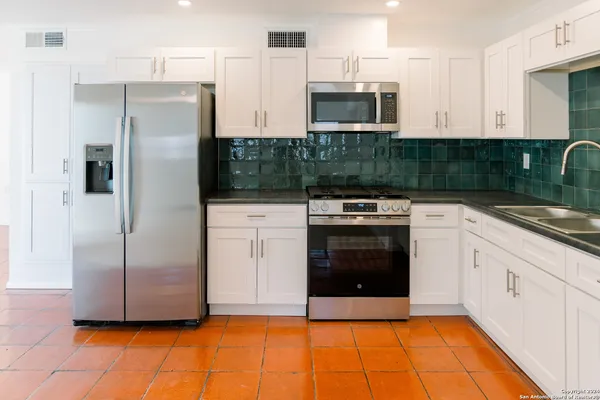 a kitchen with stainless steel appliances granite countertop a stove a refrigerator and a microwave