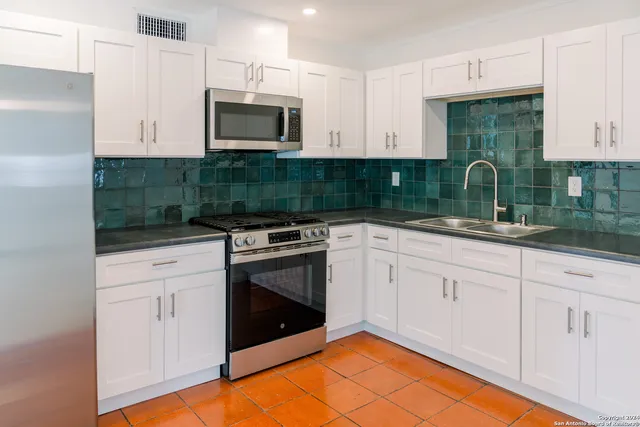 a kitchen with stainless steel appliances granite countertop a stove a sink and a microwave