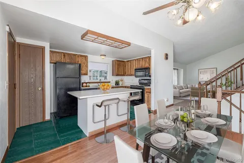 a open kitchen with stainless steel appliances granite countertop a stove a refrigerator a sink dishwasher a dining table and chairs with wooden floor