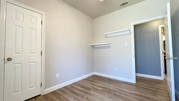 an empty room with wooden floor and closet area