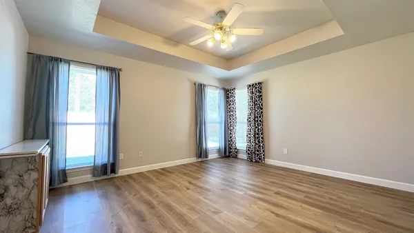 an empty room with wooden floor and windows