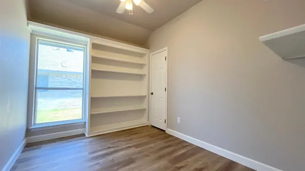 a view of an empty room with a window and wooden floor