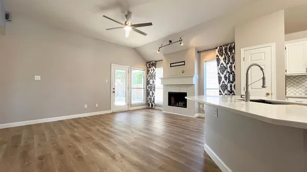 a view of a livingroom with a fireplace a ceiling fan and wooden floor