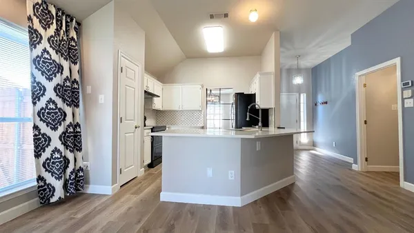 a view of kitchen with stainless steel appliances a refrigerator and a wooden floor