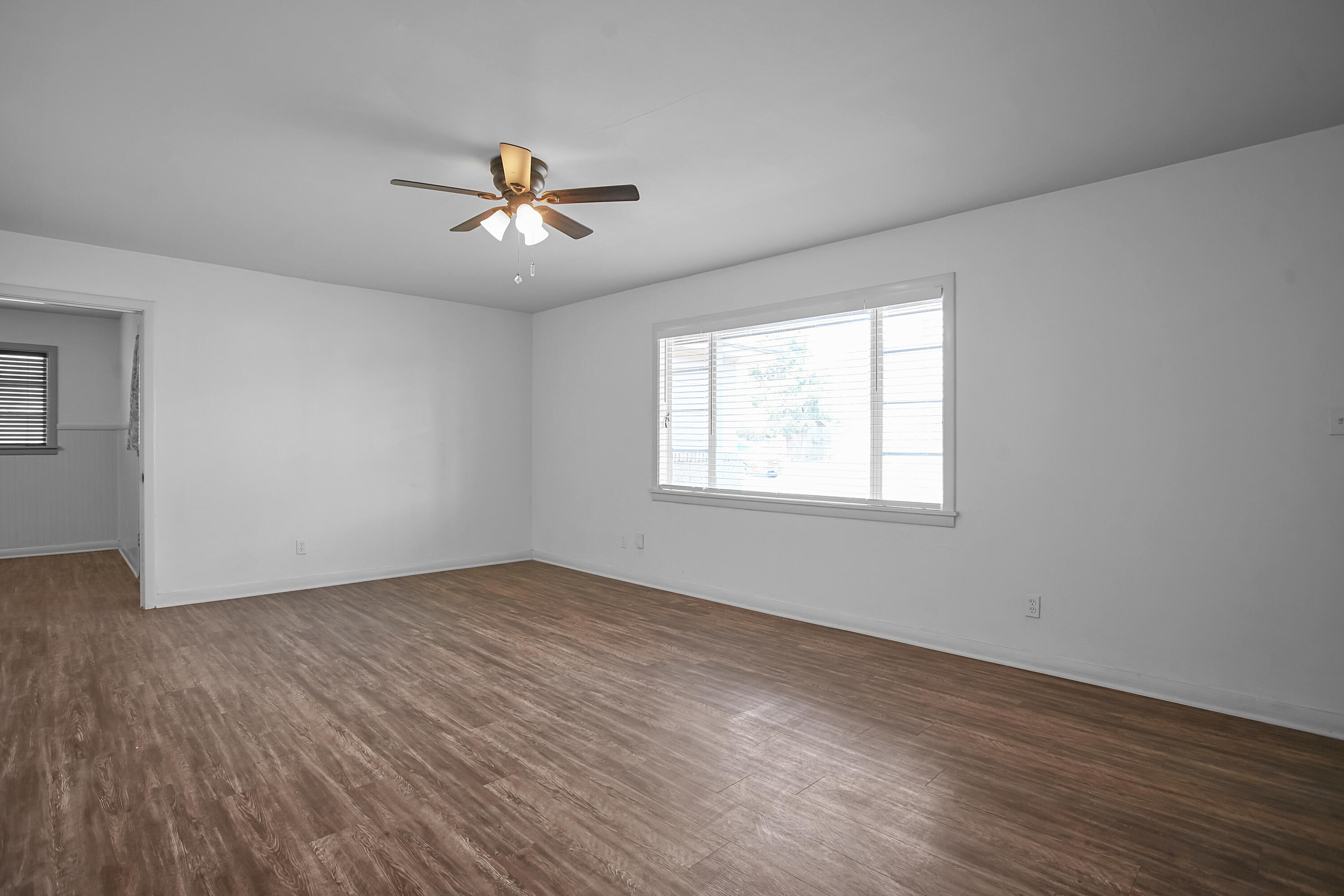 4309 31st Street Lubbock, TX 79410 - Photo 4 of 30 an empty room with wooden floor ceiling fan and windows