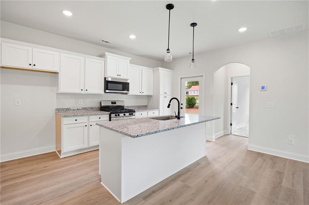 103 Winston Way Carrollton, GA 30117 - Photo 5 of 24 a kitchen with stainless steel appliances granite countertop a sink a stove a refrigerator and cabinets with wooden floor