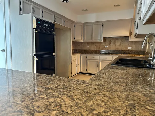 a kitchen with granite countertop a refrigerator stove and sink