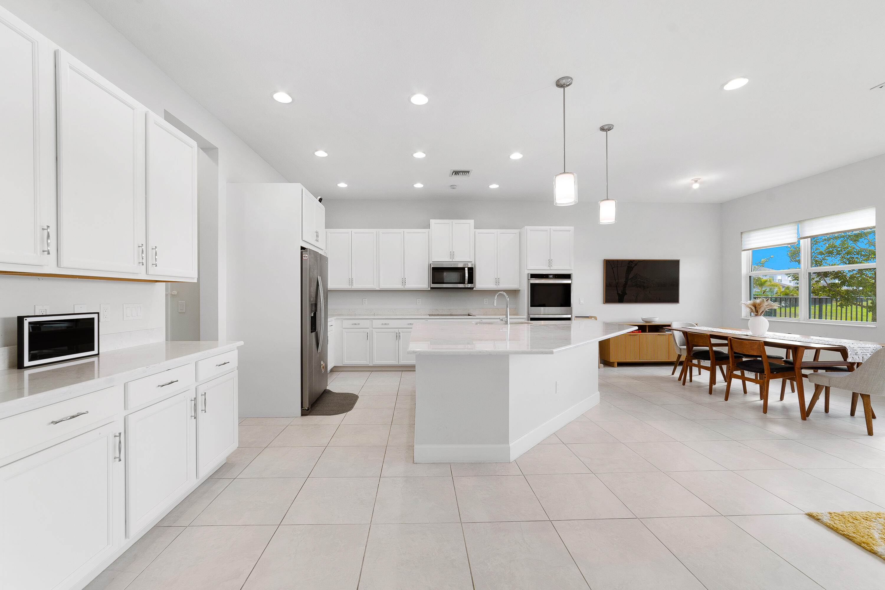 5487 Macoon Way Loxahatchee, FL 33470 - Photo 11 of 66 a large white kitchen with stainless steel appliances granite countertop a stove and white cabinets