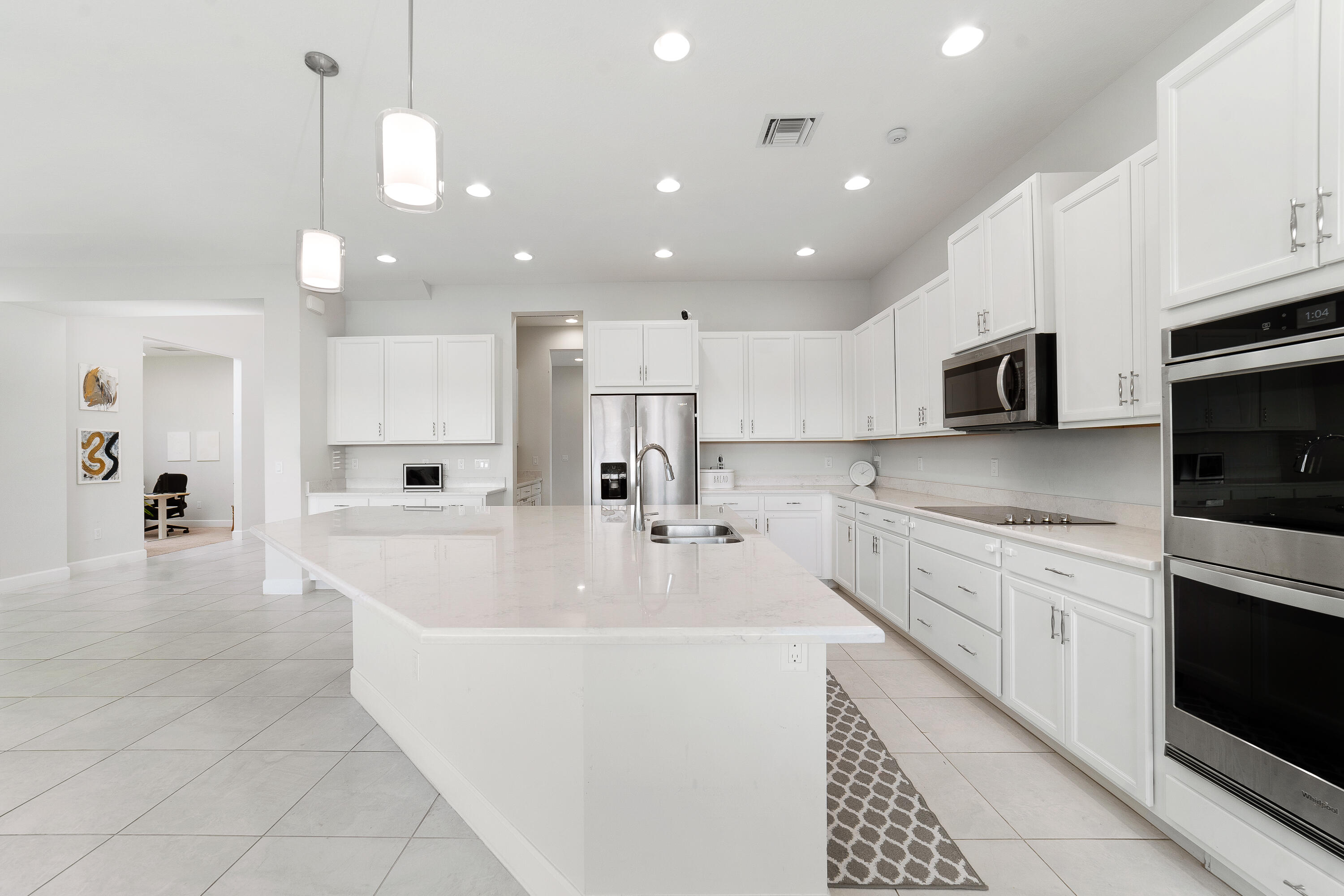 5487 Macoon Way Loxahatchee, FL 33470 - Photo 9 of 66 a large white kitchen with kitchen island a sink a stove and white cabinets