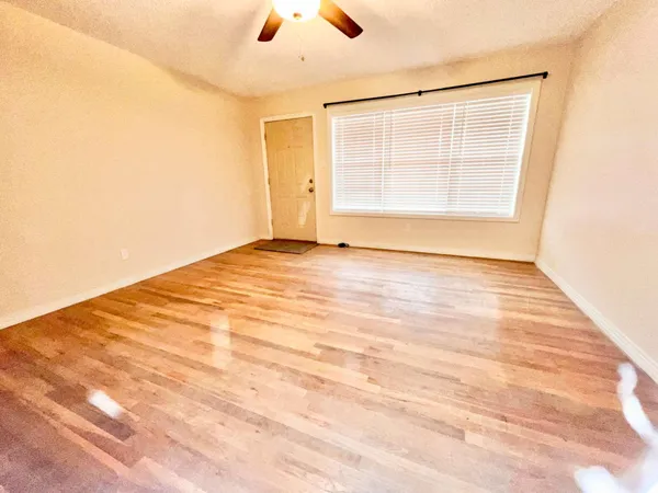 an empty room with window and wooden floor