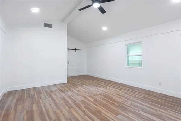 an empty room with a hardwood and ceiling fan