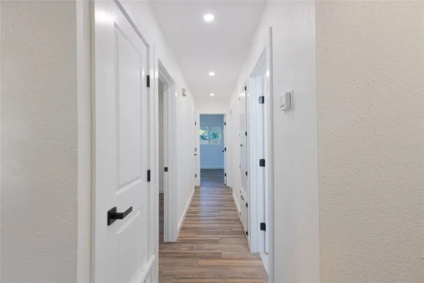 a view of a hallway with wooden floor and a bathroom