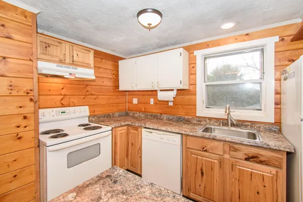 a kitchen with granite countertop a sink stainless steel appliances and a window