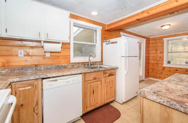 a kitchen with granite countertop cabinets a sink and a refrigerator