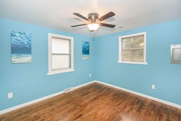 a view of a big room with wooden floor and windows