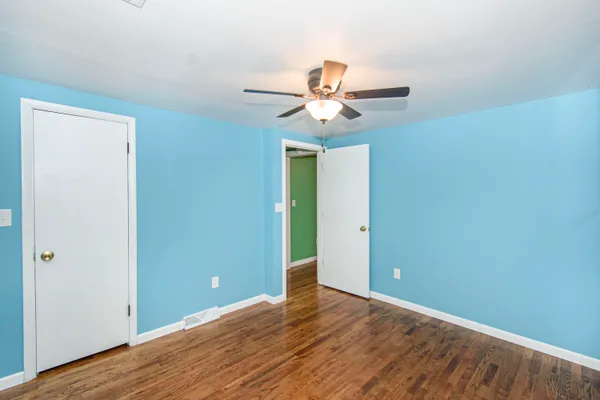 a view of a room with wooden floor and ceiling fan