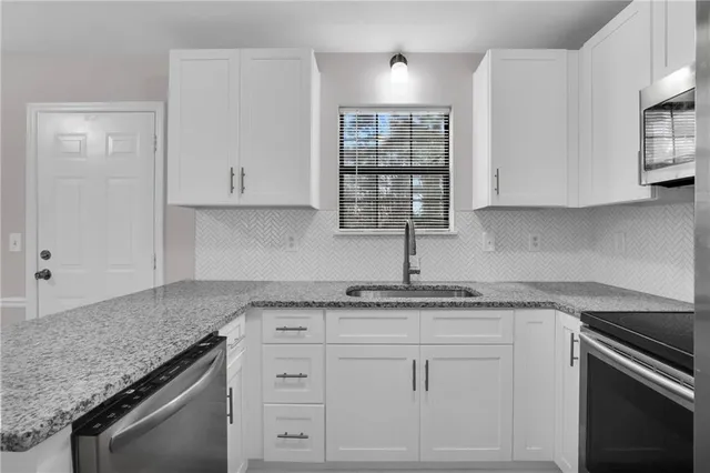 a kitchen with granite countertop white cabinets and white appliances