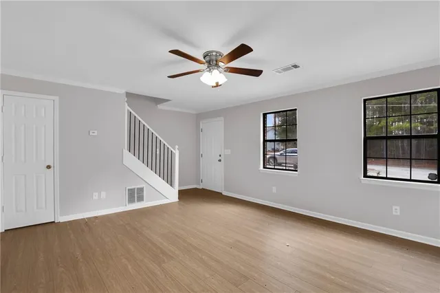 a view of an empty room with a window and wooden floor