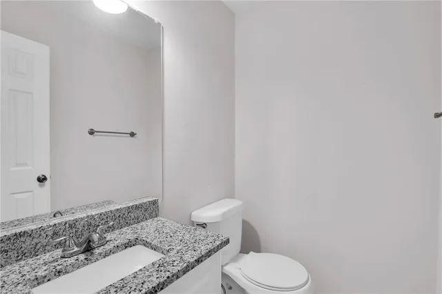 a bathroom with a granite countertop toilet and a sink