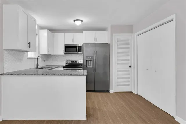a kitchen with granite countertop a refrigerator and a stove top oven