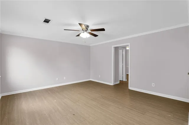 a view of empty room with wooden floor and ceiling fan