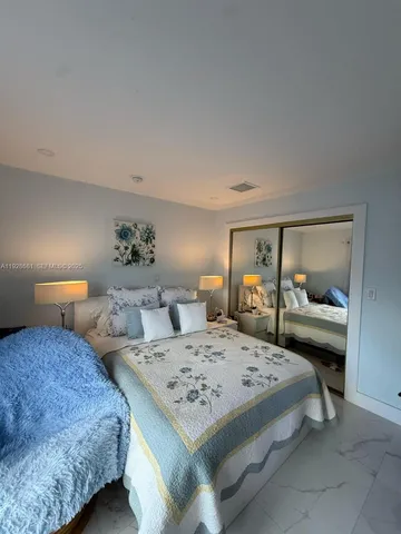 a bedroom with a bed and large mirror with a dresser