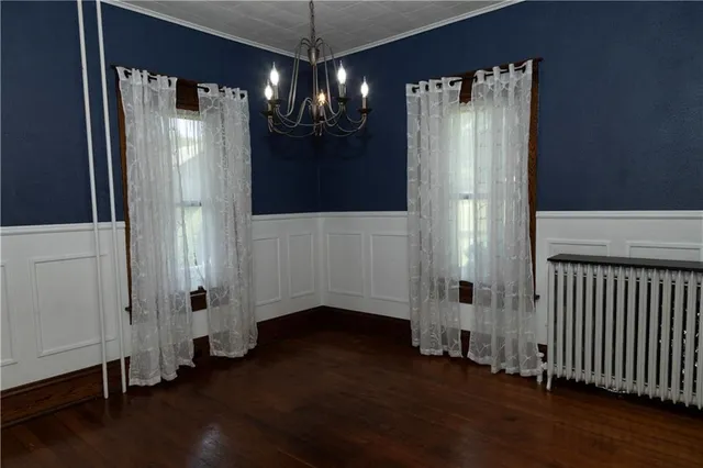 a view of a hallway with wooden floor and chandelier