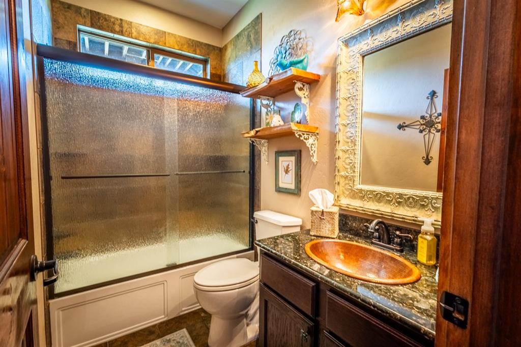 7060 Hells Gate Loop Strawn, TX 76475 - Photo 10 of 40 a bathroom with a granite countertop sink toilet and shower