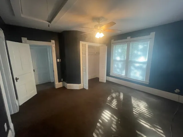 a view of an empty room with a window and a dresser
