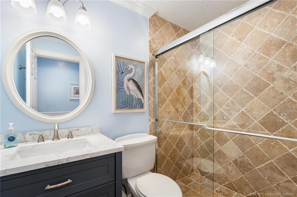 5675 Southeast Orange Street Stuart, FL 34997 - Photo 31 of 96 a bathroom with a granite countertop sink mirror a toilet and a shower