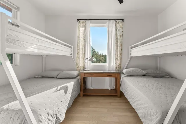 a bedroom with two beds lamp and a large window