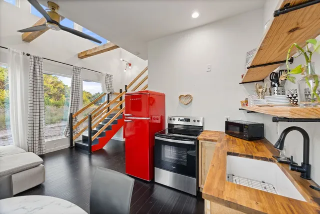a kitchen with stainless steel appliances a dining table chairs refrigerator and sink