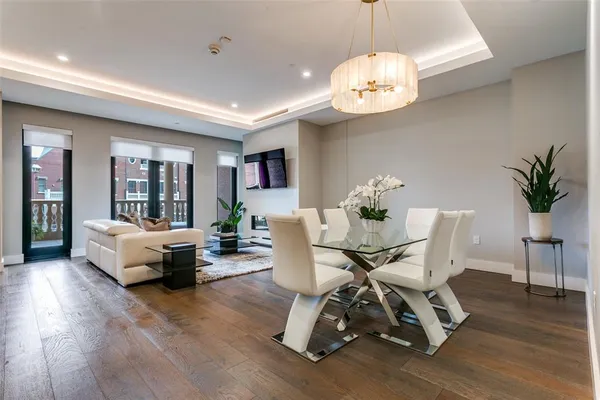 a dining room with wooden floor a chandelier a glass table and chairs
