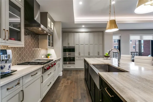 a kitchen with stainless steel appliances granite countertop a sink a stove and a wooden floors