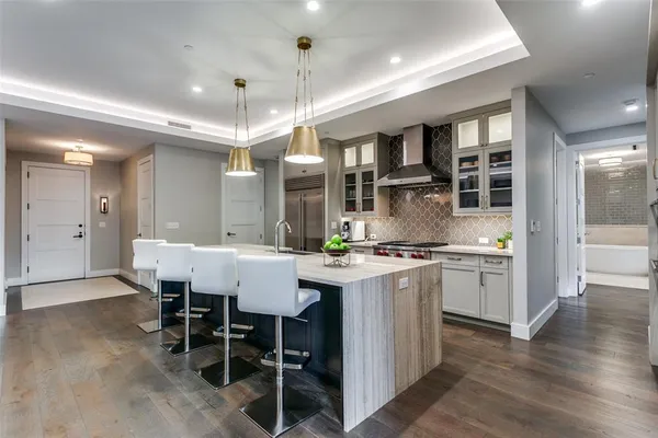 a kitchen with stainless steel appliances granite countertop a stove top oven a sink dishwasher a dining table and chairs with wooden floor