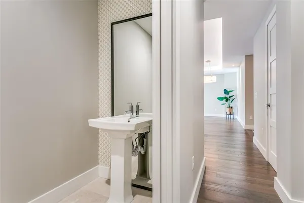 a view of a hallway with wooden floor and a bathroom