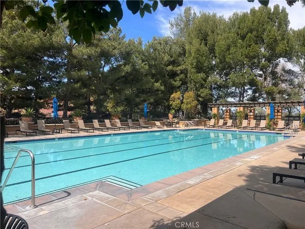 a view of swimming pool with outdoor seating and trees in the background