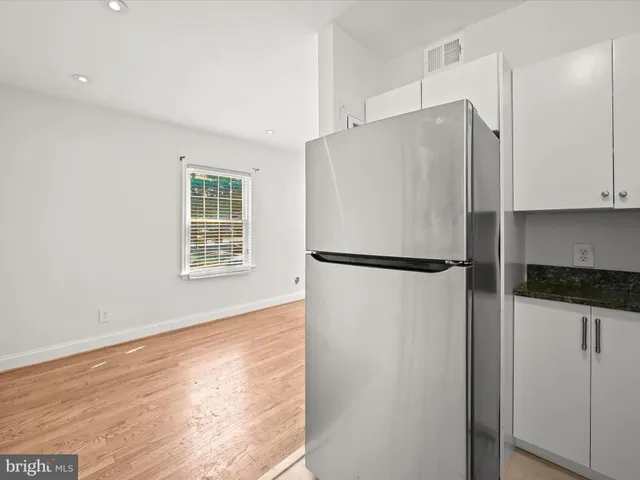 a kitchen with granite countertop a refrigerator and a stove top oven