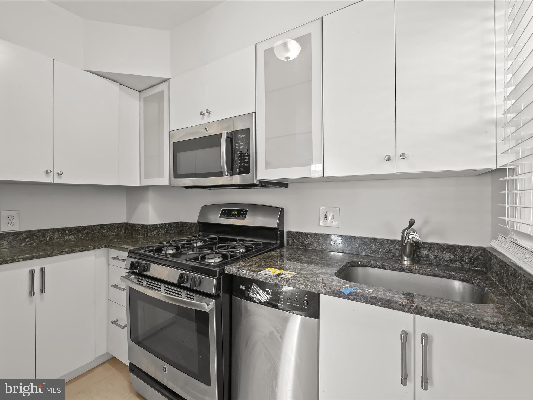 1776 East W Highway, Unit 1776 Silver Spring, MD 20910 - Photo 14 of 31 a kitchen with granite countertop white cabinets and stainless steel appliances