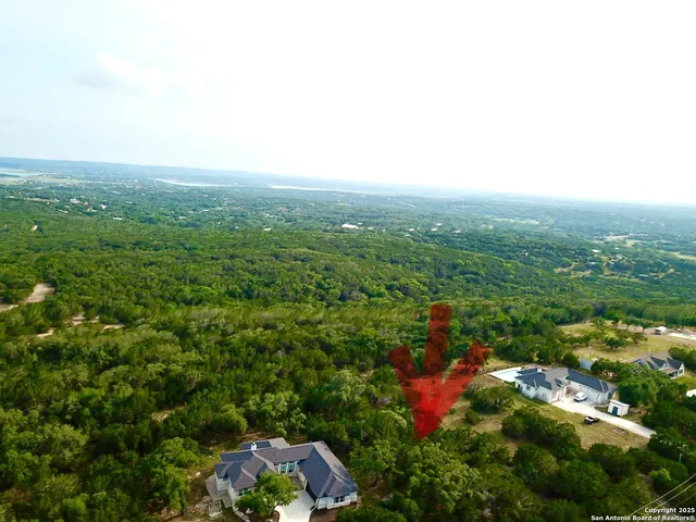 an aerial view of residential houses with outdoor space and trees
