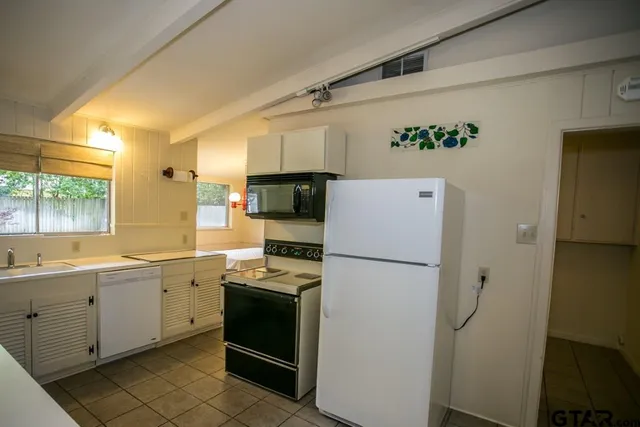 a kitchen with a refrigerator a sink and white cabinets